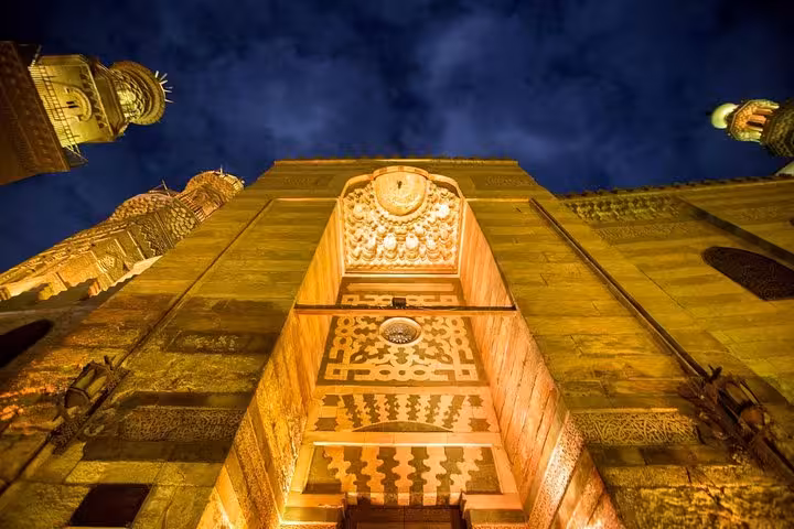 Illuminated Islamic Cairo mosque facade and minarets at night on Muizz Street day tour in Cairo