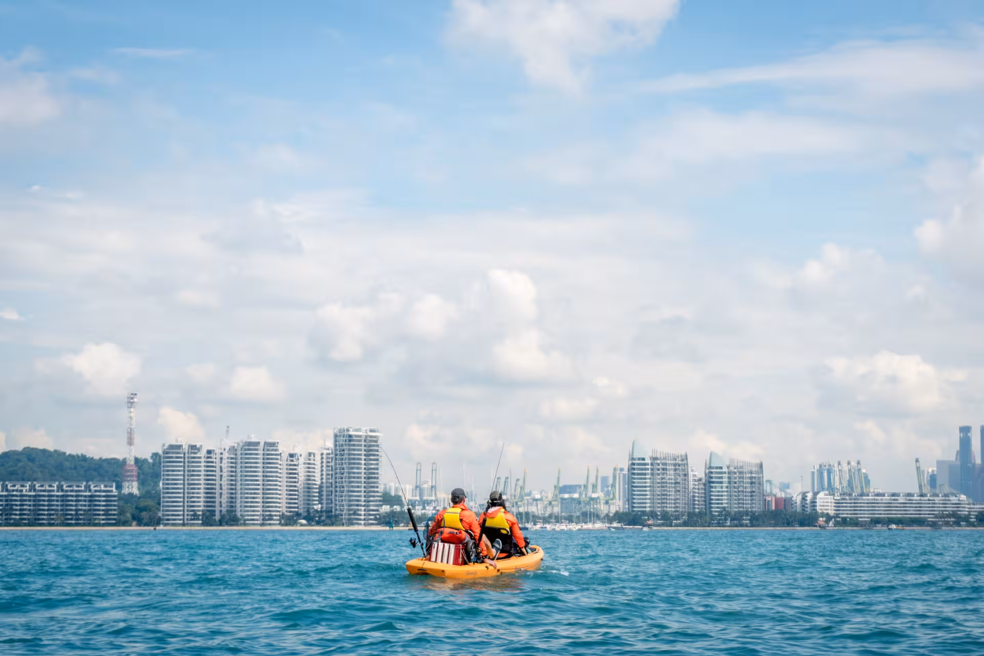 Adventurers kayak near modern skyline on Island Hopper tour, Saint John and Lazarus Islands, vibrant city backdrop.