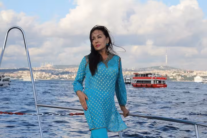 Guest on luxury yacht with Istanbul skyline and Bosphorus ferry, enjoying sunset cruise experience