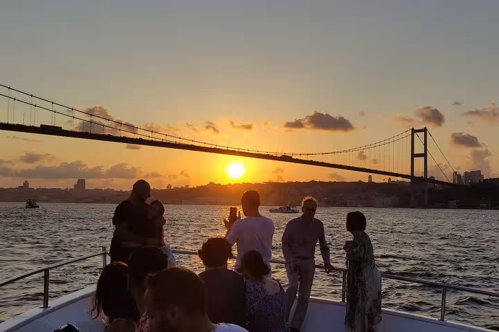 Travelers watch the sun set by the Bosphorus Bridge on an Istanbul luxury yacht cruise with wine and skyline views