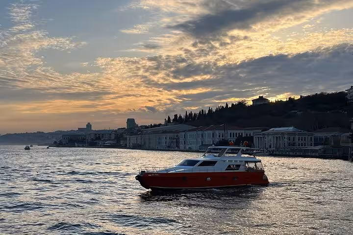 Luxurious yacht cruising the Bosphorus at sunset in Istanbul with waterfront palaces and golden sky