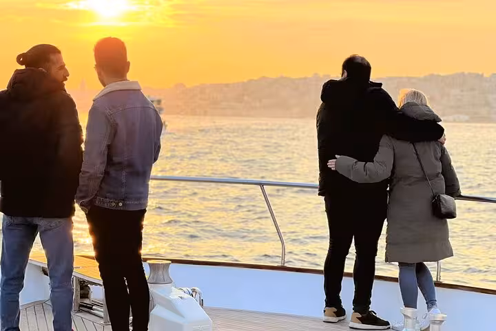 Couples watching golden sunset on an Istanbul Bosphorus luxury yacht cruise, romantic evening with wine onboard