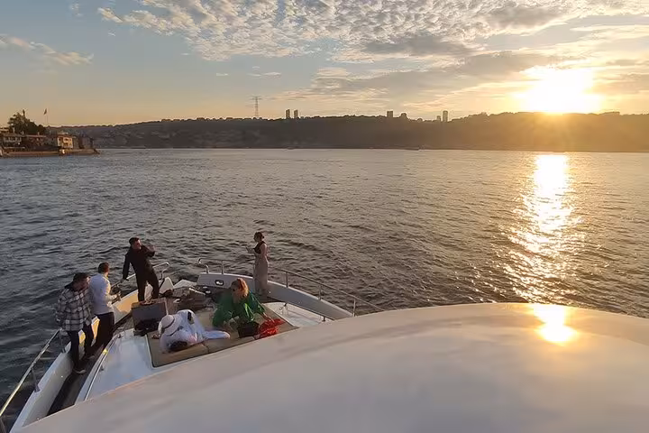 Guests relax on a luxury yacht bow during Istanbul Bosphorus sunset cruise with wine and golden reflections