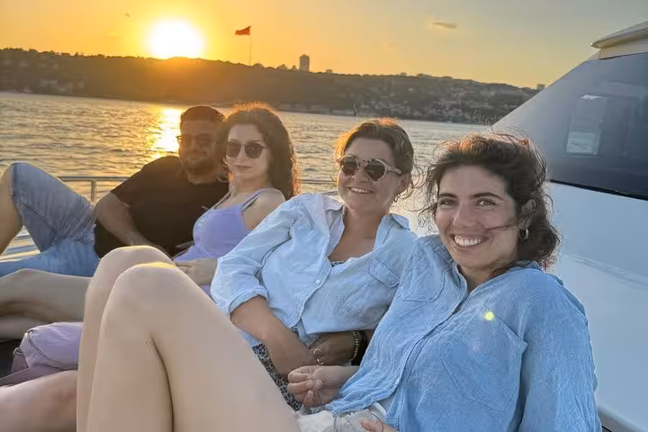 Friends relax on a luxury yacht at sunset on the Bosphorus in Istanbul, enjoying a wine cruise experience