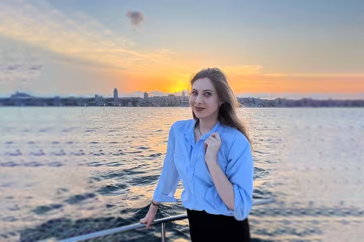 Woman posing on a luxury yacht during Istanbul Bosphorus sunset cruise, golden skyline views and wine on board