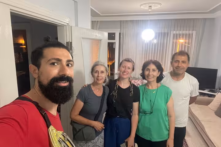 Travelers meet their Istanbul host family at a home, smiling for a group photo before a traditional Turkish dinner