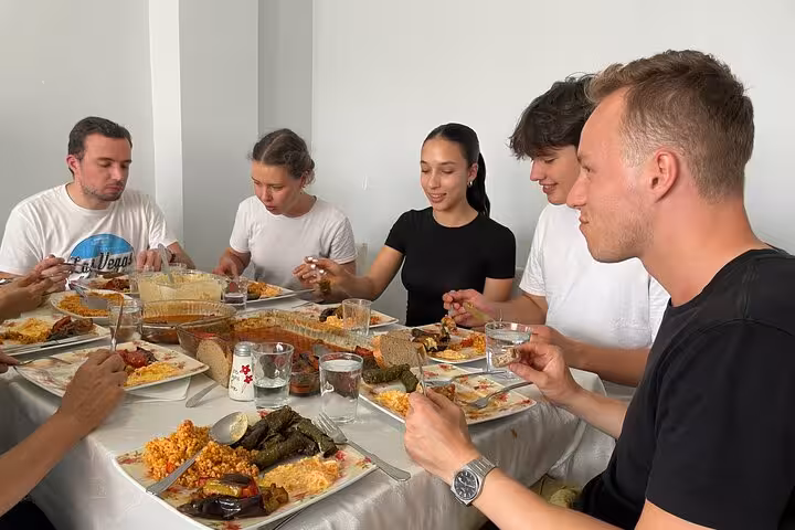 Friends enjoy homemade Turkish dishes at an Istanbul family table, tasting dolma, pilav and meze on the tour