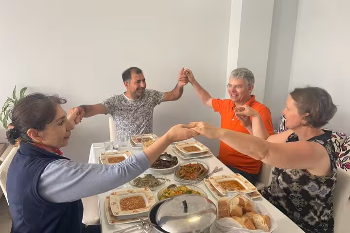 Guests join an Istanbul family dinner, sharing homemade Turkish meze and bread while holding hands at the table