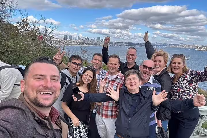 Group of tourists joyfully posing with the scenic Istanbul skyline and Bosphorus view on a Galata Port tour.