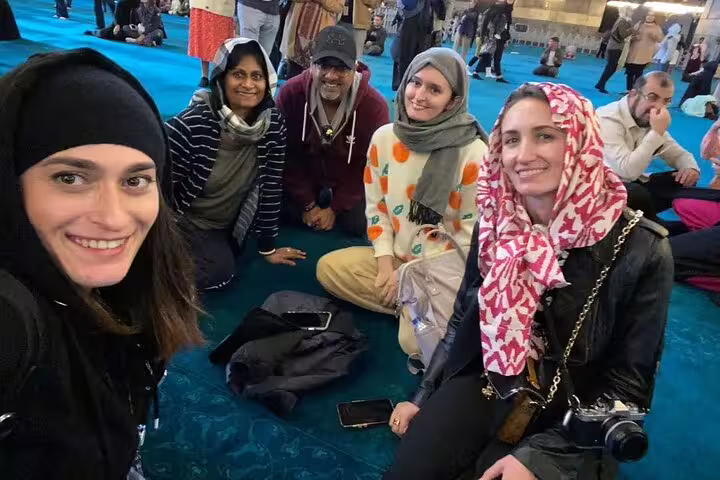 Tourists sitting on a vibrant carpet in Istanbul's iconic mosque during a private Galata Port cruise tour.