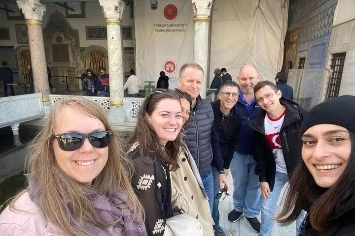 Visitors smiling in front of ornate architecture at Istanbul's historic landmarks on a private Galata Port tour.
