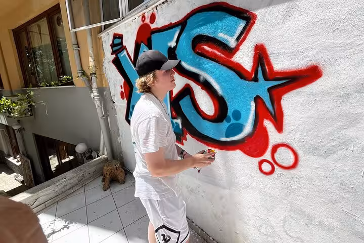 Guest spray-painting graffiti in a home garden during Istanbul street art experience with local artists