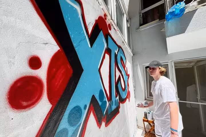 Local artist spray-painting bold graffiti in a home garden courtyard on Istanbul street art experience tour