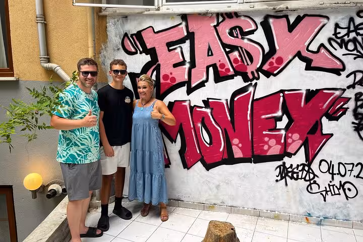 Guests pose by bold Istanbul graffiti wall during street art experience with local artists in home garden