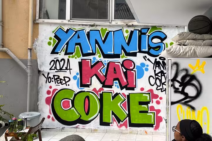 Colorful “YANNIS KAI COKE” graffiti wall at Istanbul home garden workshop on street art with locals