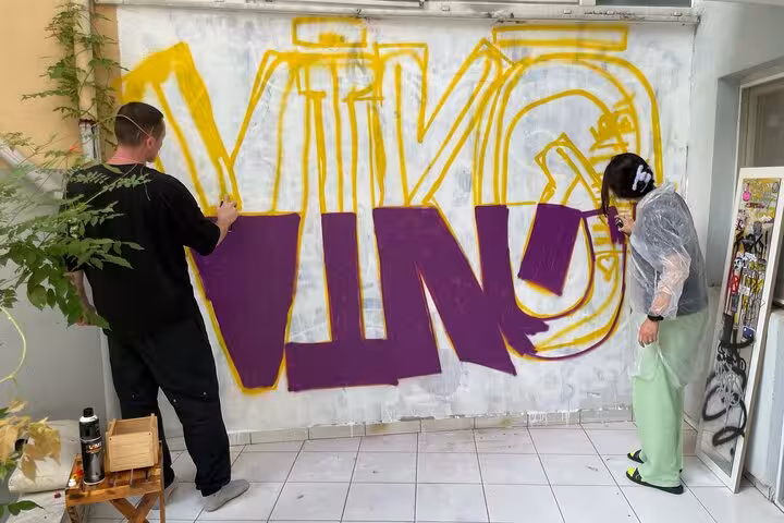 Participants spray paint graffiti letters in Istanbul home garden street art experience guided by local artists