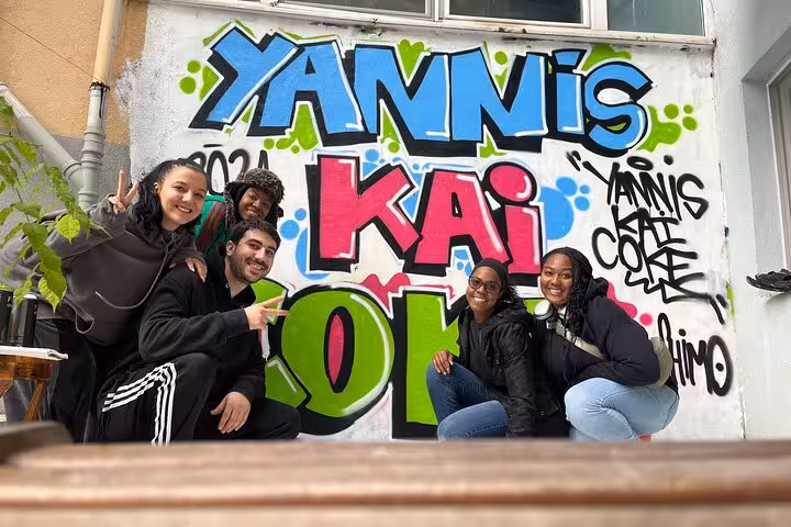 Guests pose with colorful graffiti during Istanbul street art experience with local artists in a home garden