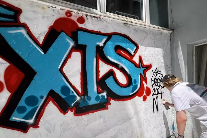 Participant spray-painting XTS graffiti mural on wall during Istanbul street art experience with local artists