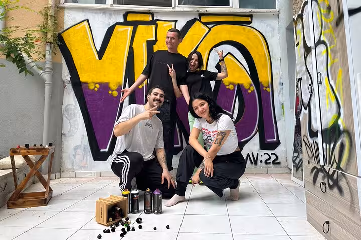 Group workshop with spray cans at Istanbul street art tour, creating bold graffiti mural in a home garden