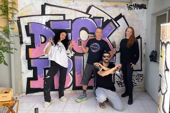 Local artists and guests hold spray cans in Istanbul home garden street art workshop with graffiti backdrop