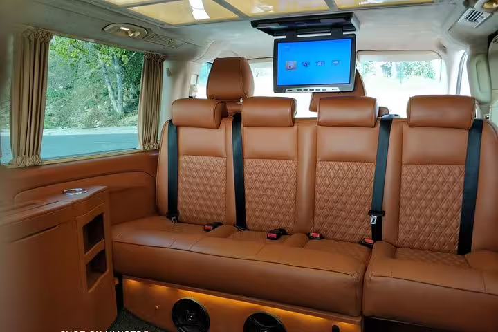 Spacious and comfortable interior of a tour van featuring plush leather seating and an entertainment system.