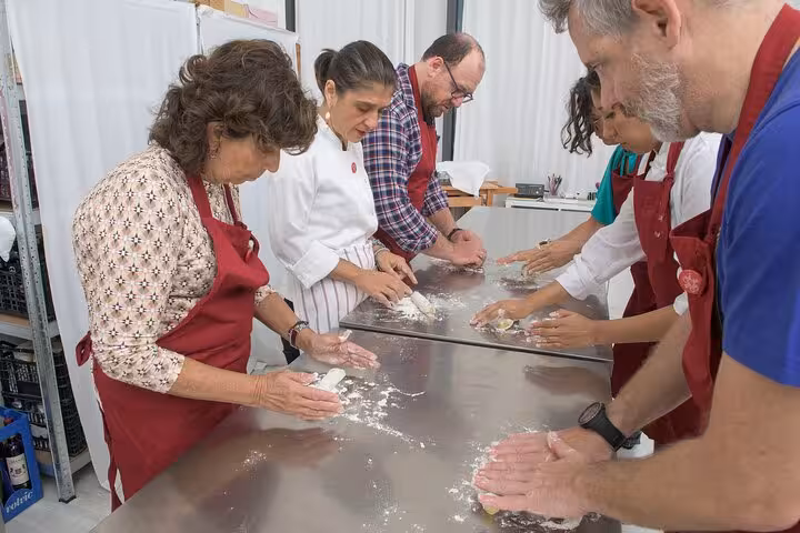 Group of people learning to make pasta from scratch with an Italian chef during a cooking class.