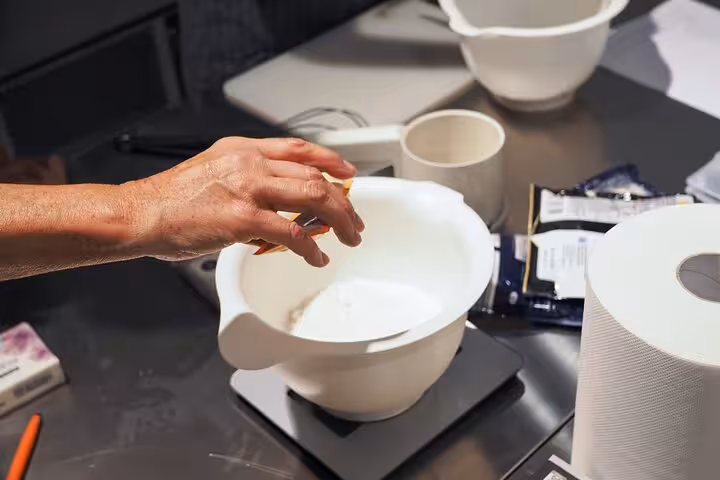 Close-up of a hand preparing ingredients in a white bowl, showcasing Italian culinary techniques.