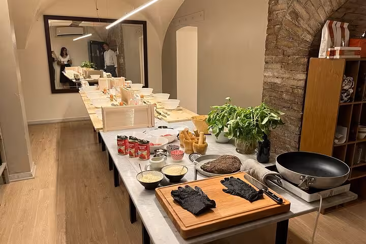Cozy cooking class setup with ingredients and utensils for fettuccine, ravioli, and tiramisù in a rustic kitchen.