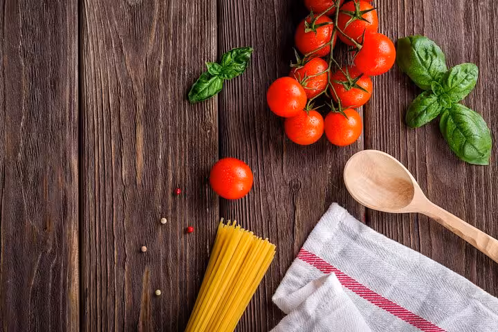 Fresh ingredients for Italian cooking class with tomatoes, basil, and spaghetti on rustic wooden table.
