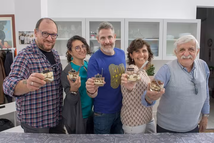 Smiling participants proudly display homemade Italian desserts, showcasing successful culinary skills after cooking class.