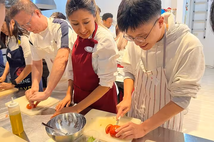 Participants enthusiastically slicing tomatoes during an interactive Italian cooking class with a professional chef.