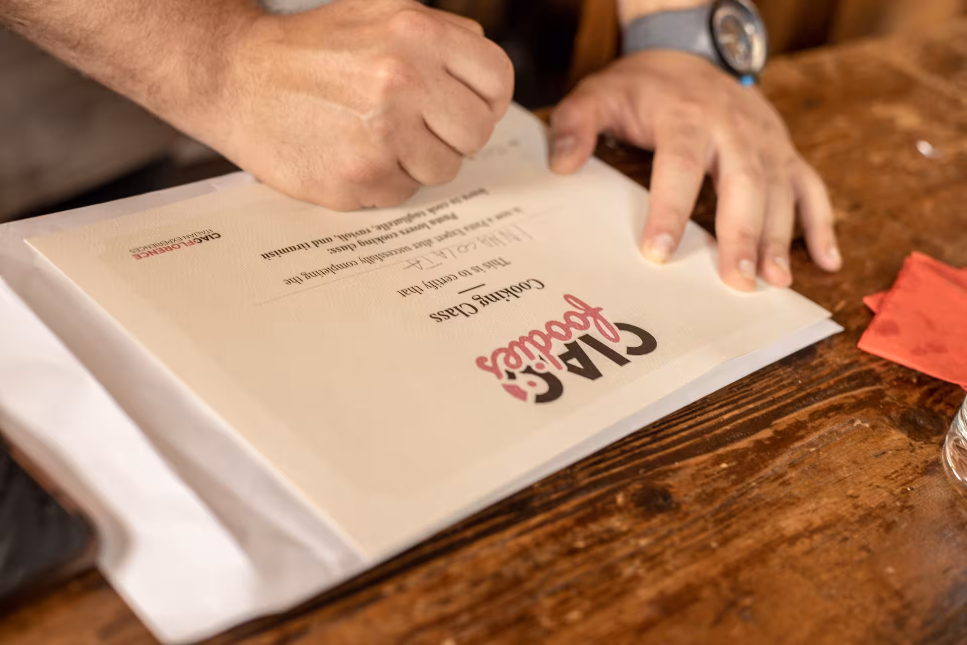 Participant signing a certificate at an Italian cooking masterclass with unlimited wine and market visit.