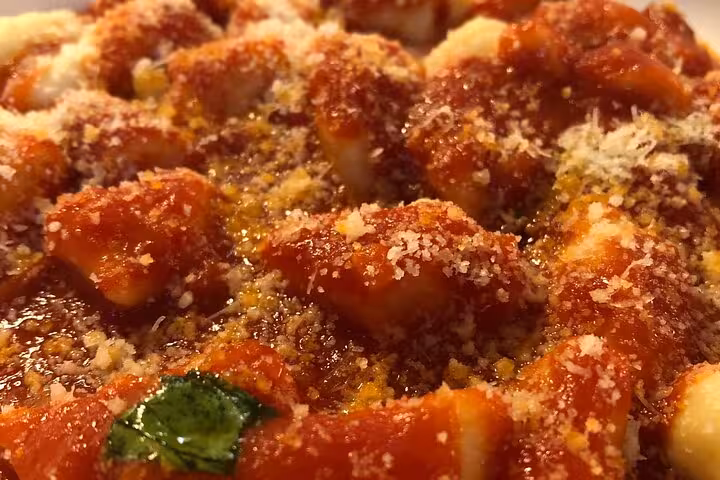 Close-up of freshly made gnocchi with rich tomato sauce and grated cheese in an Italian cooking class.