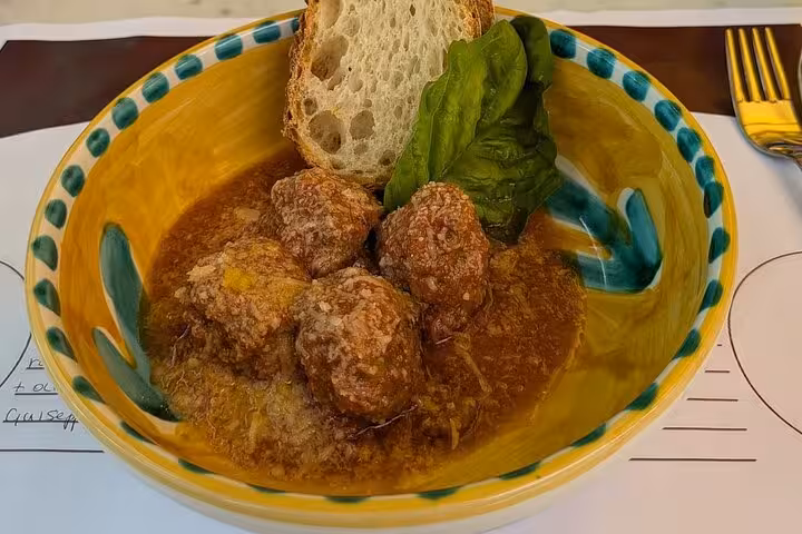 Savor Italian meatballs in rich tomato sauce with bread and basil at Sorrento's lemon tree lunch experience.