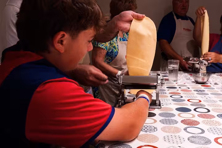 Participants enjoy making fresh pasta using a pasta machine during the Italian cooking class in Barcelona.