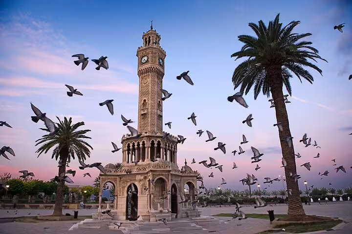 Izmir Clock Tower at sunset with palm trees and flying pigeons, scenic stop on 12-day Turkey tour