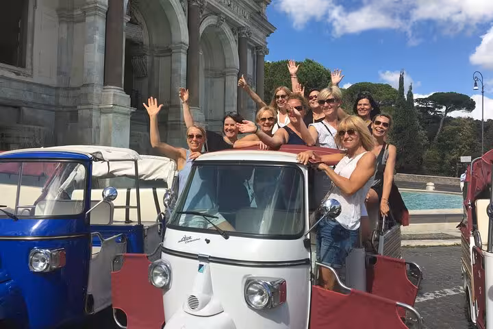 Group enjoying a James Bond Ape Calessino tour in front of historic architecture, perfect for sightseeing in style.