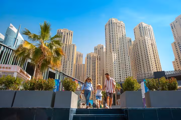 Couple strolling along JBR Beach promenade with stunning Ferris wheel view, ideal for Instagram videography.