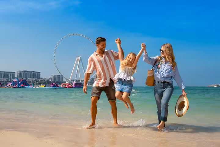 Family enjoying a fun day at JBR Beach with Ain Dubai Ferris wheel in the background, perfect for an Instagram tour.