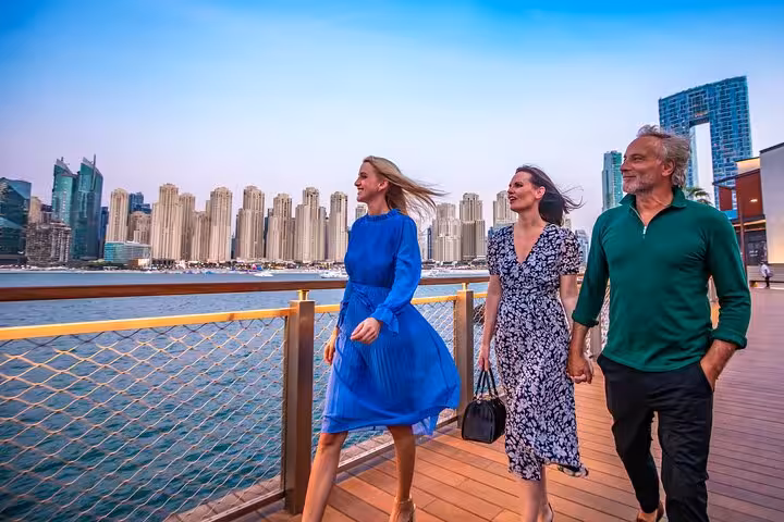 Group enjoying a scenic walk along JBR Beach promenade with Dubai Marina skyline in the background, perfect for Instagram shots.