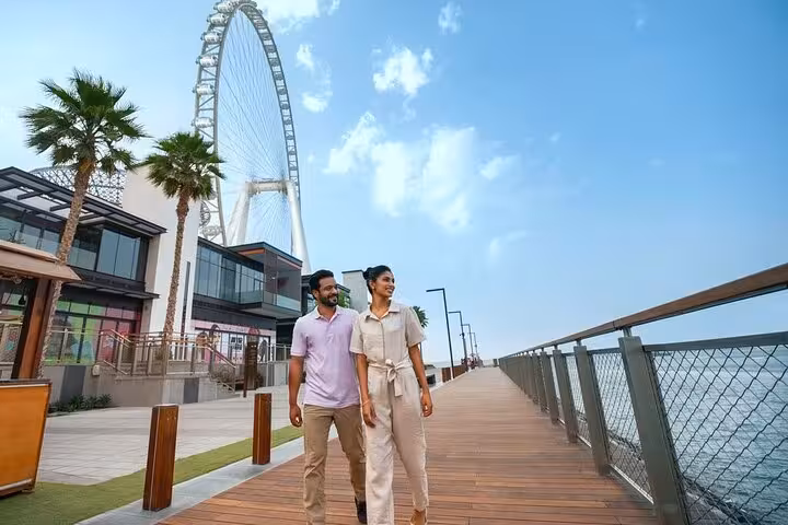 Group exploring JBR Beach with towering skyscrapers and palm trees, capturing Instagrammable cityscape scenes.