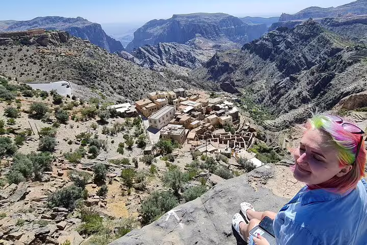 Traveler enjoying stunning view of Jebel Akhdar Al Suwjara Village nestled in Oman’s rugged mountain landscape.