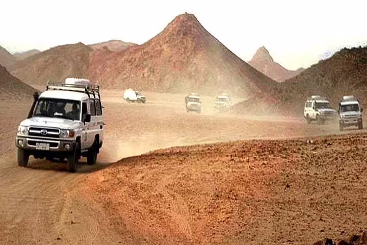 4x4 convoy racing across rugged desert track on Jeep super safari adventure before quad biking and stargazing