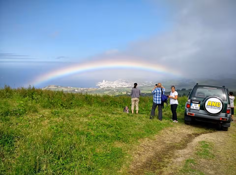 Jeep off-road viewpoint in Sete Cidades with travelers watching a rainbow over São Miguel’s coast