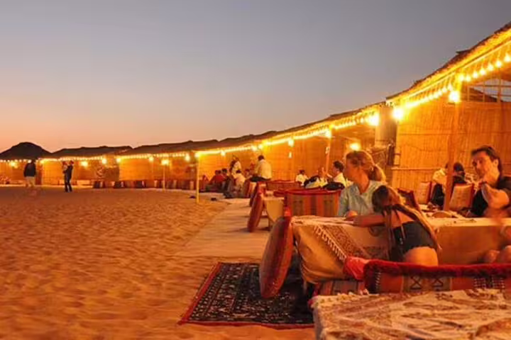 Guests relaxing at sunset Bedouin camp with lights and dinner on Jeep safari adventure tour in Marsa Alam