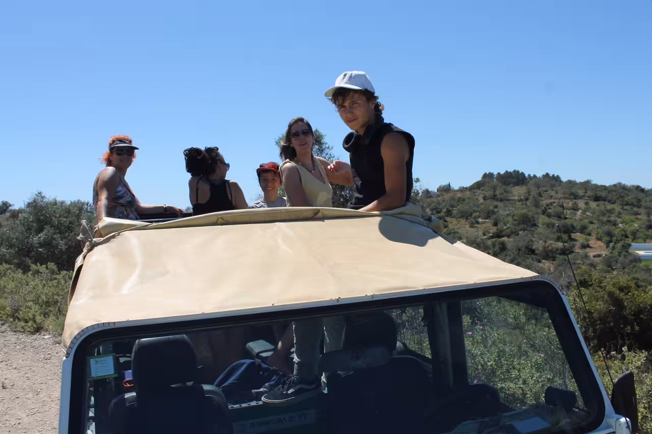 Guests riding in open-top Jeep on Algarve coast safari tour, heading to Benagil cliffs under clear blue sky