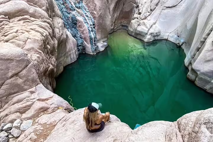 Traveler overlooking Lost Lake turquoise oasis on Jeep safari from Sharm El Sheikh to Dahab, Sinai canyon