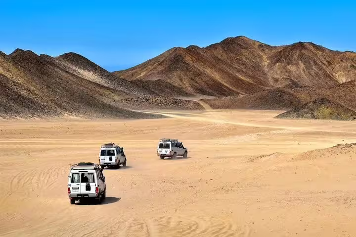4x4 jeep convoy crossing Marsa Alam desert valleys and mountains on safari adventure tour with dinner show