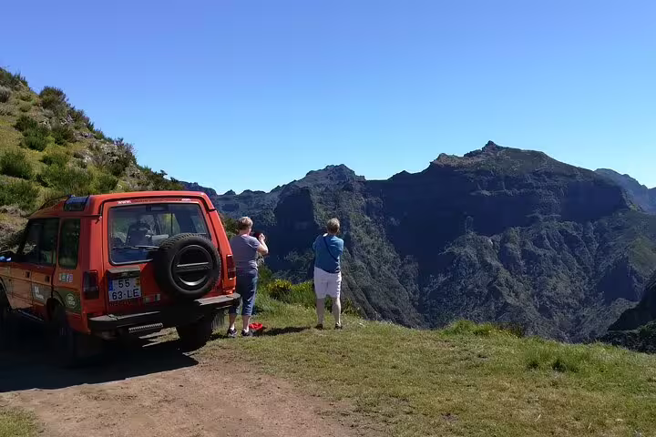 Visitors admire the stunning mountain vistas of Câmara de Lobos from a scenic Jeep tour stop in Madeira.
