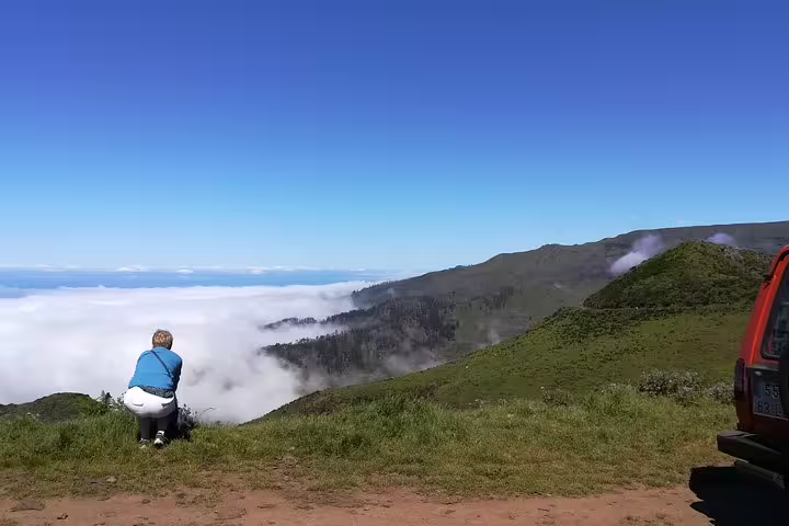 Traveler enjoying breathtaking views of lush mountains and clouds on a Jeep Tour in Câmara de Lobos, Madeira.